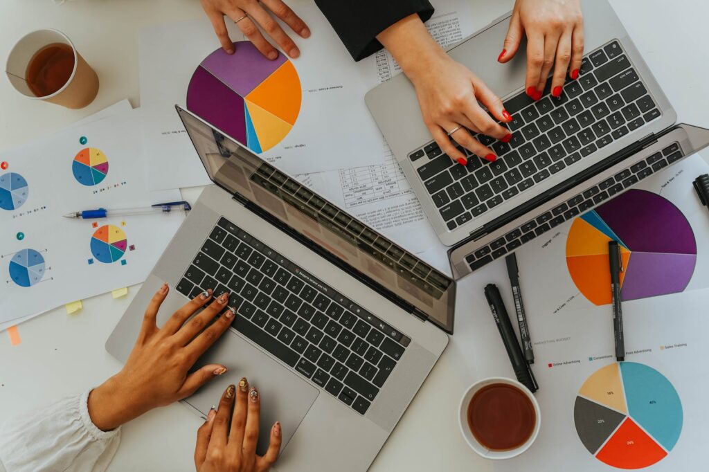 persons using laptops on table with charts